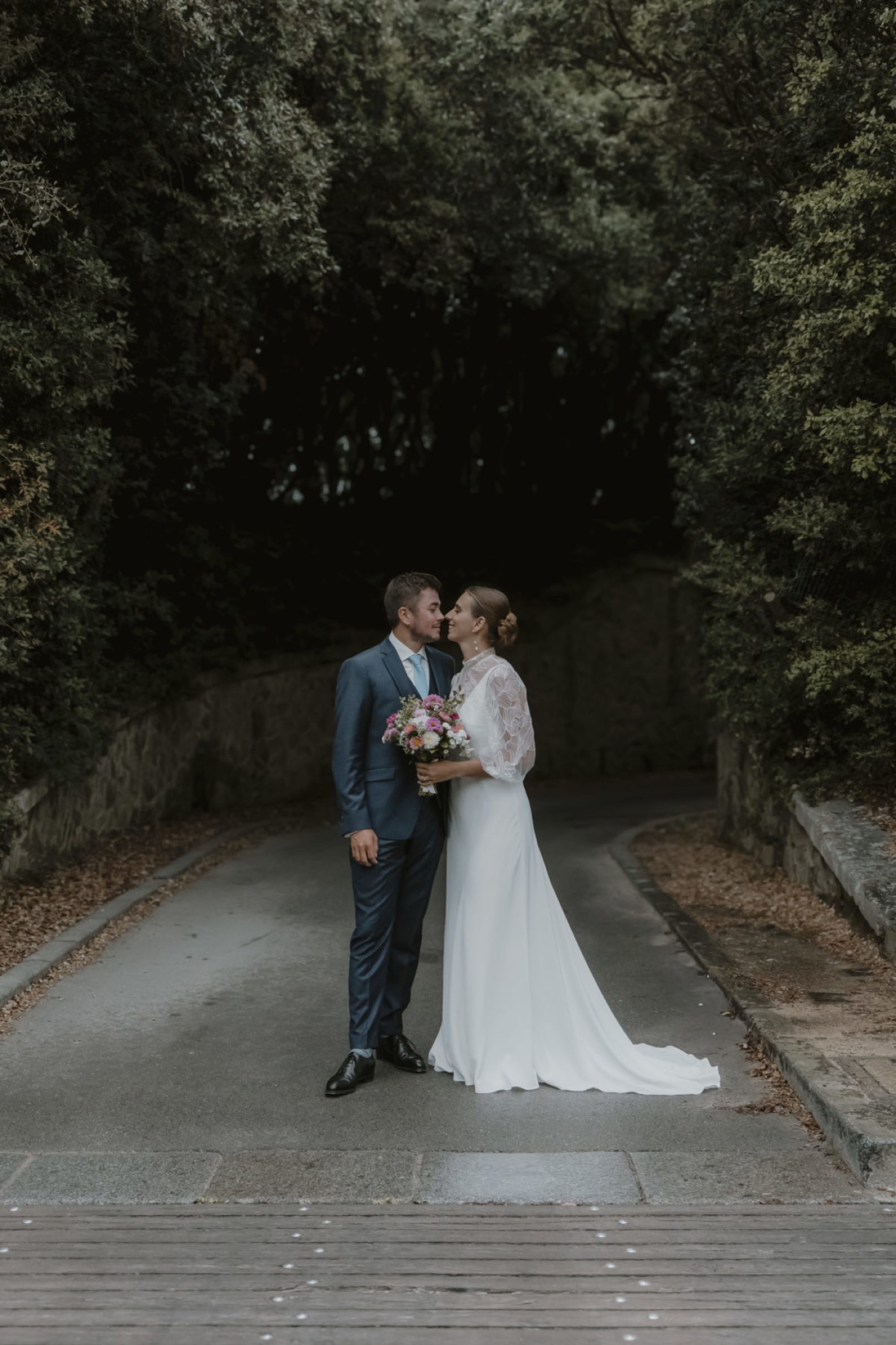 Un marié et une mariée sur un chemin bordé d’arbres à l’Île d’Yeu