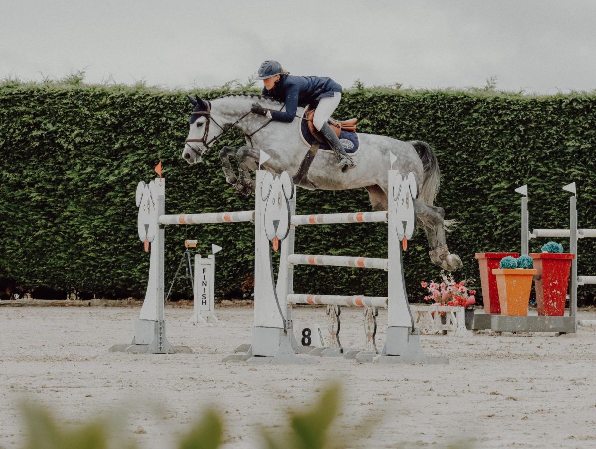 Cavalière franchissant un obstacle en concours de saut