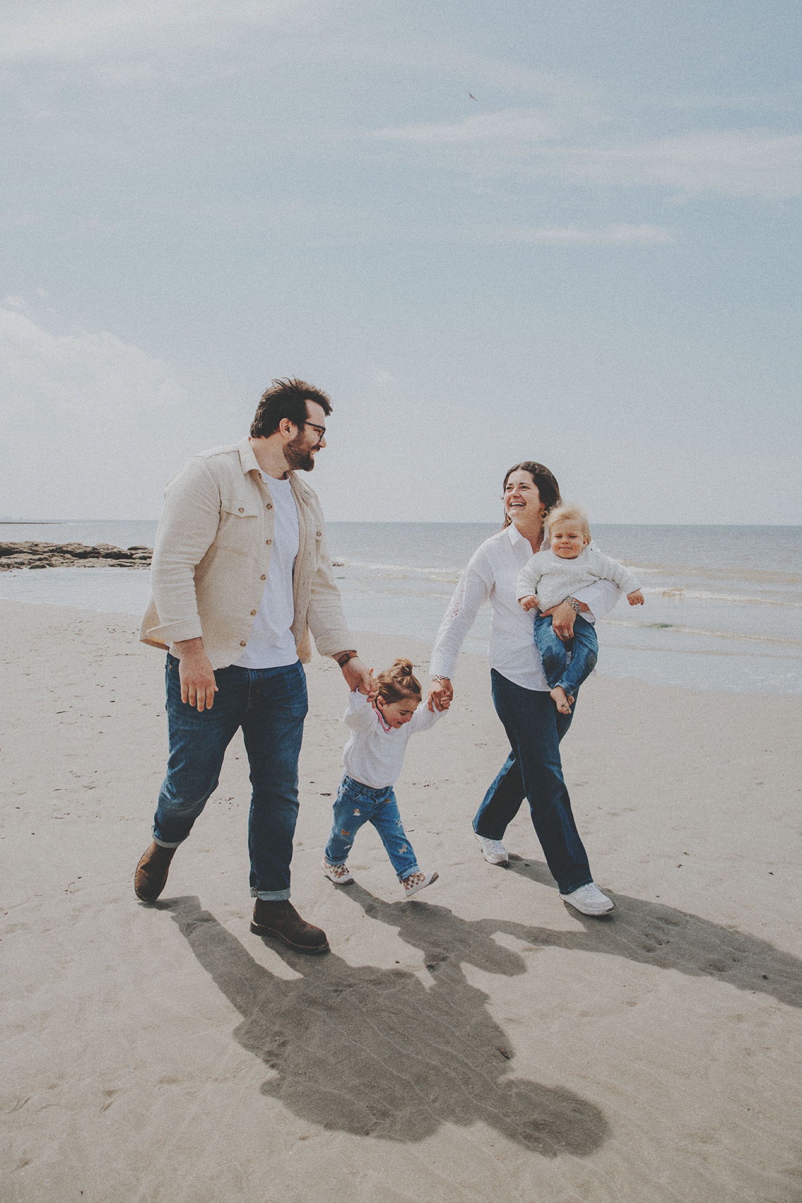 Famille de quatre marchant main dans la main sur la plage